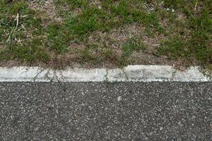 asfaltweg met strepen en groen gras textuur achtergrond, lege kopie ruimte. foto