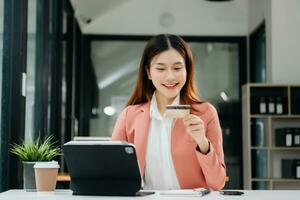 vrouw gebruik makend van slim telefoon voor mobiel betalingen online winkelen, omni kanaal, zittend Aan tafel, virtueel pictogrammen grafiek koppel scherm foto