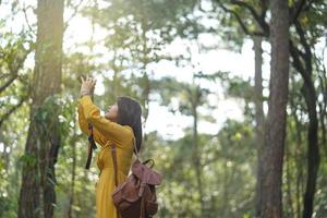 aantrekkelijk aziatisch vrouwenavontuur in het bos dat natuurlijk bezienswaardigheden bezichtigt en met behulp van camera een foto maakt bij vakantiereisconcept holiday