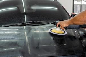 auto detaillering - man bezig met polijsten en verzorgen van de buitenkant met wax. automatisch polijsten met machine foto