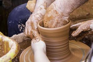 handen van de mens die klei bewerkt en vormgeeft, pottenbakker in aardewerk foto