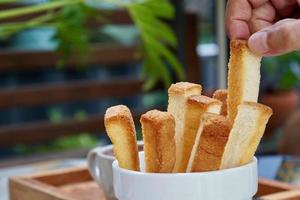 twee vingers die een krokant brood uit een wit kommetje pinken foto