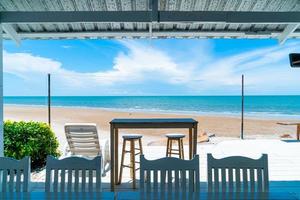 houten bar en stoel met oceaanzeestrand en blauwe hemelachtergrond foto