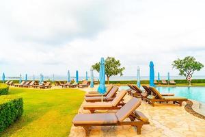 stoel zwembad of bed zwembad en parasol rond zwembad met zee strand achtergrond in pattaya in thailand foto