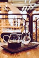 koude druppel zwarte koffiepot met glas en ijs in het café en restaurant van de coffeeshop foto