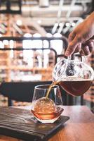 koude druppel zwarte koffiepot met glas en ijs in het café en restaurant van de coffeeshop foto