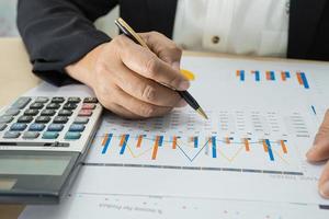 Aziatische accountant werkt en analyseert financiële rapporten projectboekhouding met grafiekgrafiek en rekenmachine in modern kantoor, financiën en bedrijfsconcept. foto