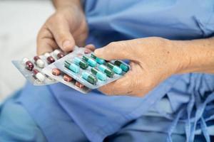 aziatische arts houdt en giet antibiotica pillen geneeskunde uit de fles naar patiënt voor behandeling infectie in ziekenhuisapotheek drogisterij concept. foto
