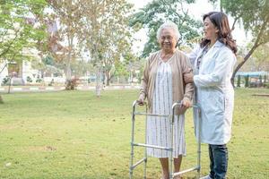 dokter helpt en verzorgt aziatische senior of oudere oude dame vrouw gebruikt rollator met een sterke gezondheid tijdens het wandelen in het park in een fijne frisse vakantie.