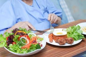 Aziatische senior of oudere oude dame vrouw patiënt ontbijt plantaardig gezond voedsel eten met hoop en gelukkig zittend en hongerig op bed in het ziekenhuis. foto