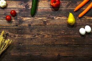 houten tafel met voedsel vrij voor tekst wortels eieren tomaten komkommer appel Peer knoflook foto