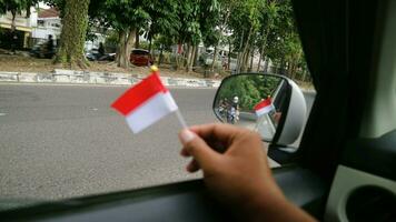 hand- Holding Indonesisch vlag in de auto naar Welkom Indonesië's onafhankelijkheid dag foto