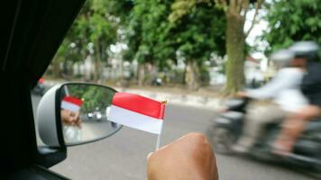 hand- Holding Indonesisch vlag in de auto naar Welkom Indonesië's onafhankelijkheid dag foto
