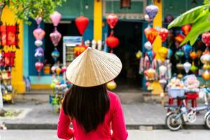 jong vrouw toerist in Vietnamees traditioneel jurk op zoek Bij een souvenir winkel in Hoi een oude stad- foto