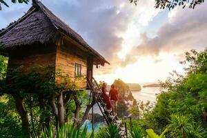 jong paar reiziger genieten van en op zoek mooi zonsopkomst Bij de boom huis in nusa penida eiland Bali, Indonesië foto