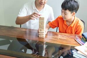 Aziatisch vader en zoon spelen hout blokken spel zorgeloos kind spelen hout blokken spel gebouw bouwer van blokken met vader Bij huis foto