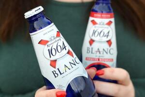 jong meisje houdt 1664 kronenbourg blanc bier glas buitenshuis. 1664 blanc is de tarwe bier van de Frans brouwerij kronenbourg geëxporteerd wereldwijd foto