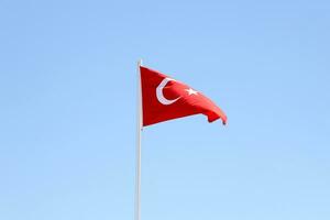 Turks vlag Aan vlaggenmast golvend in schoon blauw lucht achtergrond foto