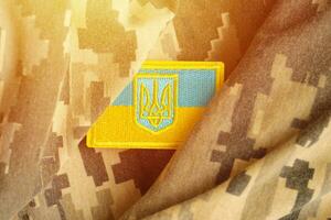 leger camouflage kleding stof met oekraïens vlag Aan uniform chevron foto