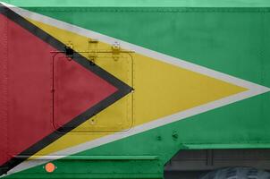 Guyana vlag afgebeeld Aan kant een deel van leger gepantserd vrachtauto detailopname. leger krachten conceptuele achtergrond foto