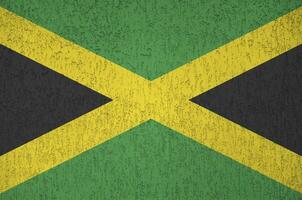 Jamaica vlag afgebeeld in helder verf kleuren Aan oud Verlichting bepleistering muur. getextureerde banier Aan ruw achtergrond foto