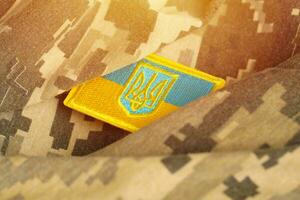 leger camouflage kleding stof met oekraïens vlag Aan uniform chevron foto