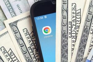 smartphone scherm met google chroom app en veel van honderd dollar rekeningen. bedrijf en sociaal netwerken concept foto