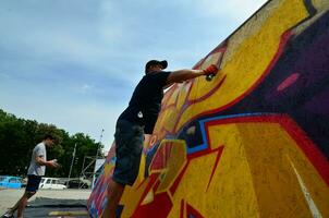 Charkov, Oekraïne - mei 27, 2017 festival van straat kunsten. jong jongens trek graffiti Aan portable houten muren in de centrum van de stad. de werkwijze van schilderij Aan muren met aërosol verstuiven blikjes foto