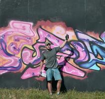 jong Kaukasisch mannetje graffiti artiest tekening groot straat kunst schilderij in blauw en roze tonen foto