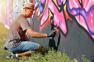 jong Kaukasisch mannetje graffiti artiest tekening groot straat kunst schilderij in blauw en roze tonen foto