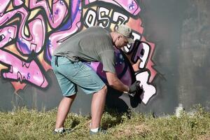 jong Kaukasisch mannetje graffiti artiest tekening groot straat kunst schilderij in blauw en roze tonen foto