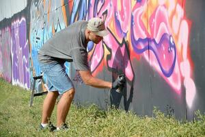 jong Kaukasisch mannetje graffiti artiest tekening groot straat kunst schilderij in blauw en roze tonen foto