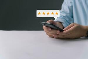 klant recensie tevredenheid terugkoppeling enquête concept, Mens hand- drukken Aan smartphone scherm met goud vijf ster evalueren kwaliteit van onderhoud ranking van bedrijf. foto