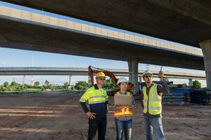 bouw plaats arbeiders en ingenieurs van divers nationaliteiten zijn bespreken plannen. twee bouw arbeiders werken samen terwijl bezoekende snelweg bouw foto