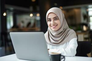 portret van mooi moslim vrouw leerling online aan het leren in koffie winkel, jong vrouw met hijab studies met laptop in cafe, meisje aan het doen haar huiswerk foto