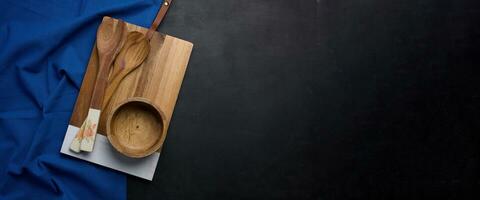 leeg rechthoekig houten keuken snijdend bord, leeg kom en houten lepels Aan zwart tafel top visie foto