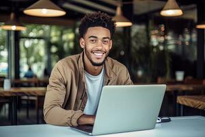 portret van vrolijk zwart mannetje leerling aan het leren online in koffie winkel, jong Afrikaanse Amerikaans Mens studies met laptop in cafe, aan het doen huiswerk foto