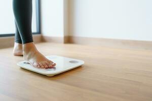 verliezen gewicht. dik eetpatroon en schaal voeten staand Aan elektronisch balans voor gewicht controle. meting instrument in kilogram voor eetpatroon. foto