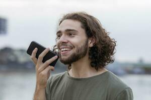 portret van gelukkig jong Mens gebruik makend van smartphone buitenshuis foto