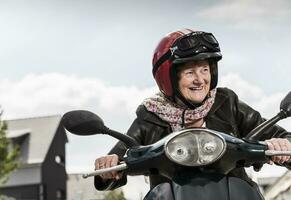 actief senior dame rijden motor scooter in de stad foto