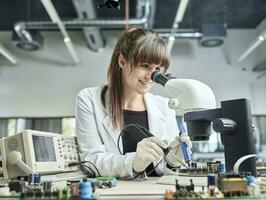 vrouw technicus solderen onder microscoop foto