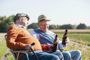 twee oud vrienden zittend in de velden, drinken bier, pratend over oud keer foto