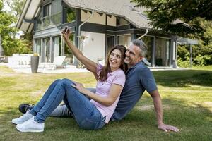 gelukkig paar zittend in tuin van hun huis nemen een selfie foto