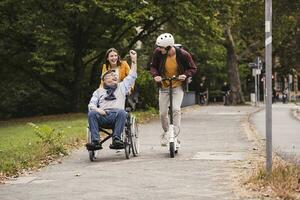 senior Mens in rolstoel hebben pret met zijn volwassen kleinkinderen buitenshuis foto