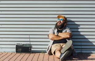 portret van gebaard Mens met portable radio genieten van zonlicht foto