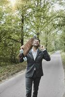 gelukkig zakenman met skateboard pratend Aan smartphone Aan landelijk weg foto