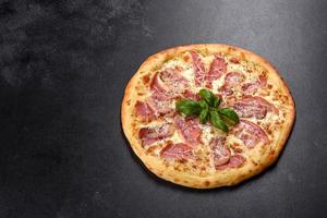 heerlijke verse krokante pizza uit de oven met ham, kaas en basilicum foto