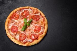 smakelijke verse ovenpizza met tomaten, kaas en basilicum op een betonnen ondergrond foto