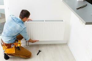 Mens is repareren radiator accu in de kamer. onderhoud reparatie werken vernieuwing in de vlak. verwarming restauratie. moersleutel in handen. foto