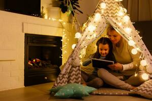 jong moeder met haar dochter spelen, Holding handen en op zoek Bij elk andere lachend. zacht pastel tafereel, . tent lodge in de kinderkamer. moeder dag foto